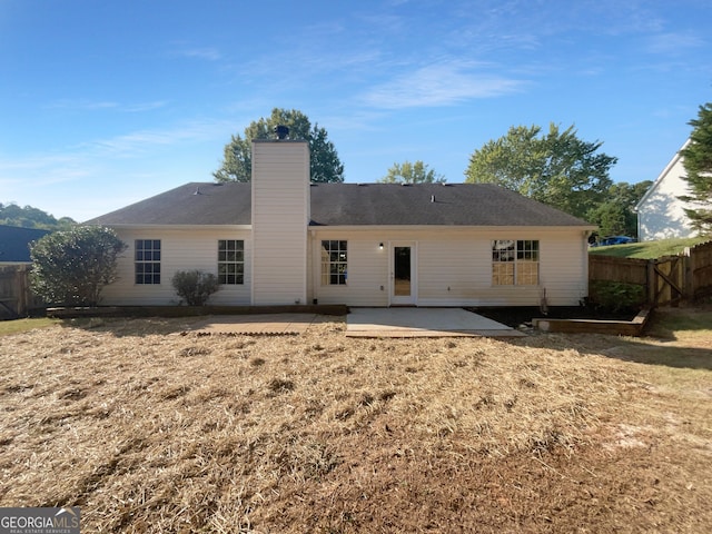 back of property with a patio, a chimney, and fence