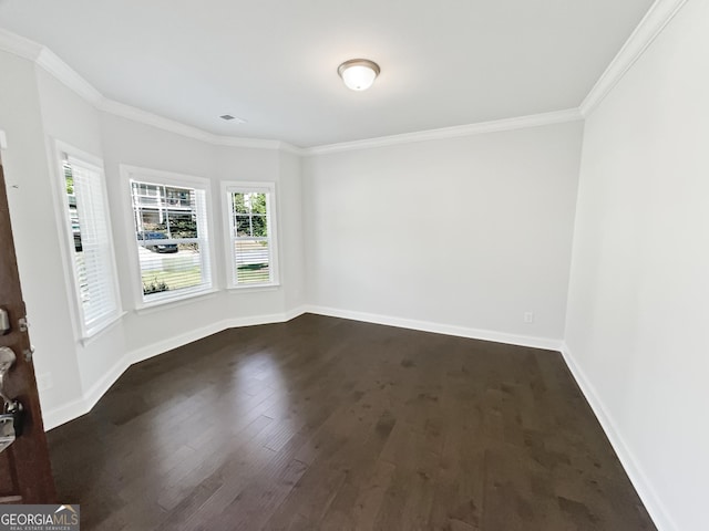 spare room featuring dark wood-style floors, visible vents, ornamental molding, and baseboards