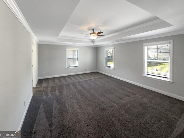 unfurnished room featuring baseboards, ceiling fan, ornamental molding, a tray ceiling, and dark carpet