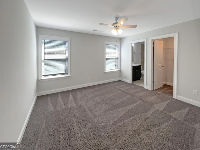 unfurnished bedroom featuring carpet floors, visible vents, baseboards, and a walk in closet