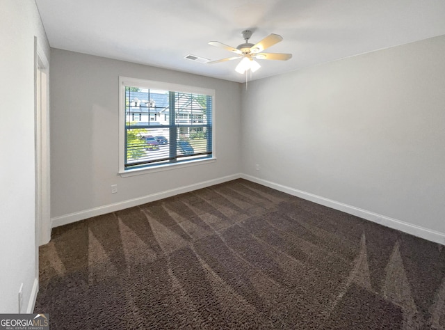 spare room with baseboards, visible vents, dark colored carpet, and a ceiling fan