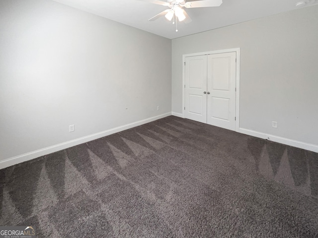 unfurnished bedroom featuring a ceiling fan, baseboards, dark colored carpet, and a closet