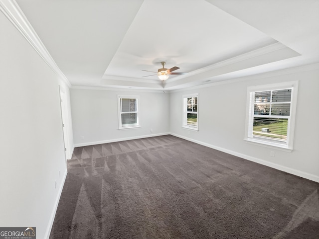 unfurnished room featuring baseboards, a raised ceiling, ceiling fan, ornamental molding, and dark colored carpet