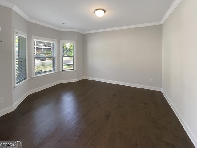 spare room with baseboards, ornamental molding, and dark wood-style flooring