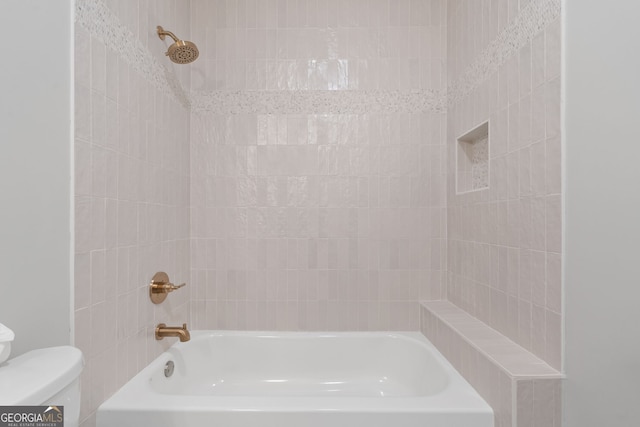 bathroom with tiled shower / bath combo and toilet