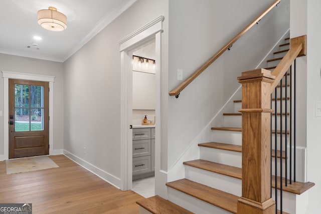 foyer entrance with light hardwood / wood-style floors and ornamental molding