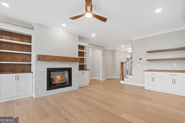 unfurnished living room with a fireplace, light wood-type flooring, ceiling fan, and ornamental molding