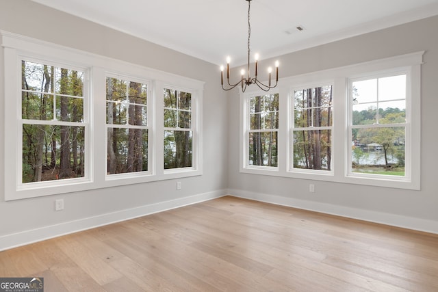 unfurnished dining area with a wealth of natural light, a notable chandelier, and light wood-type flooring