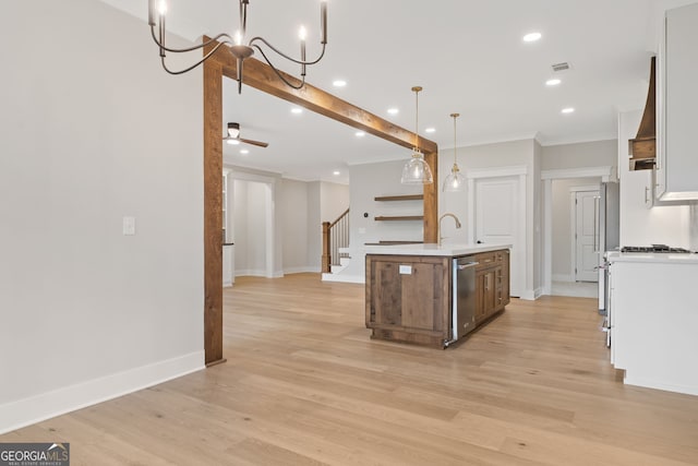 kitchen with dishwasher, a kitchen island with sink, ceiling fan with notable chandelier, hanging light fixtures, and light hardwood / wood-style flooring