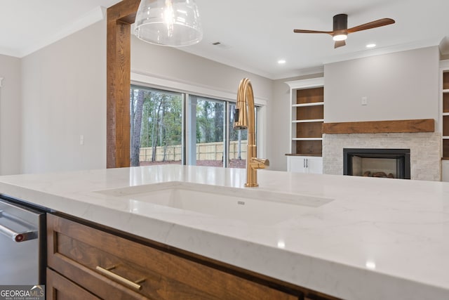 kitchen featuring sink, light stone countertops, a fireplace, and hanging light fixtures