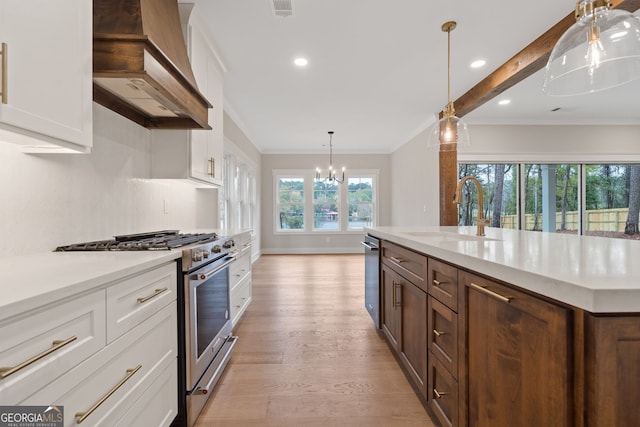 kitchen with white cabinets, wall chimney range hood, sink, light hardwood / wood-style flooring, and stainless steel appliances