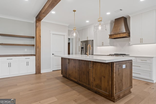 kitchen featuring an island with sink, light wood-type flooring, and custom exhaust hood