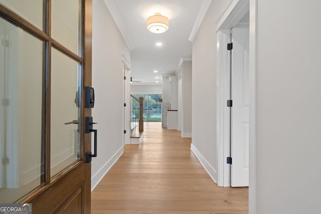 corridor with light hardwood / wood-style floors and crown molding