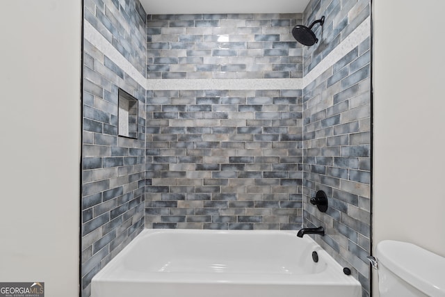 bathroom with tiled shower / bath combo and toilet