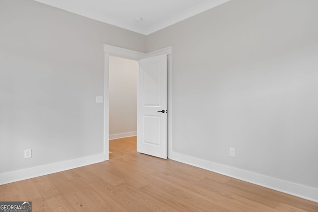 empty room with crown molding and light hardwood / wood-style floors