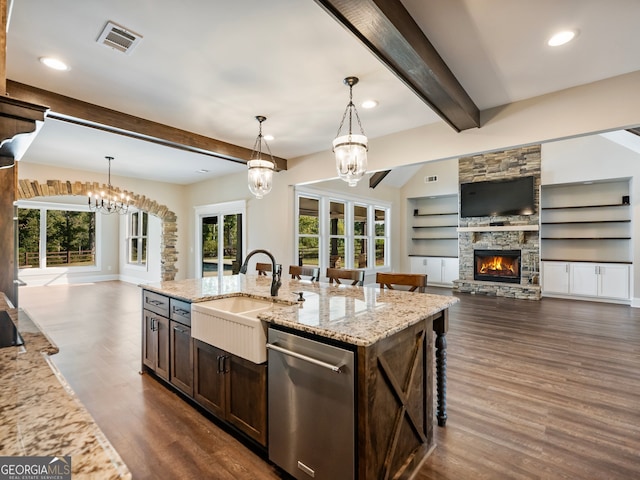 kitchen with an inviting chandelier, light stone countertops, a fireplace, dishwasher, and sink