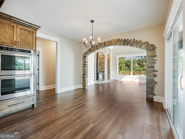 kitchen with dark wood-type flooring, double oven, decorative light fixtures, and a notable chandelier