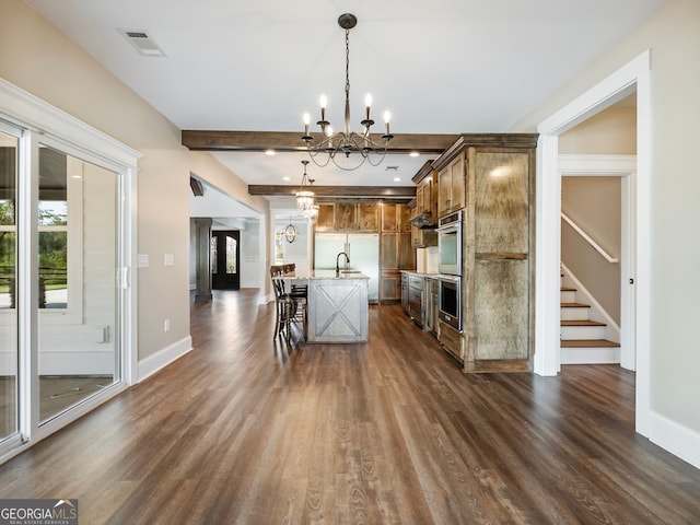 kitchen featuring an inviting chandelier, a kitchen breakfast bar, decorative light fixtures, dark hardwood / wood-style flooring, and a center island with sink