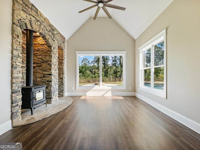 unfurnished living room with dark wood-type flooring, high vaulted ceiling, ceiling fan, and a wood stove