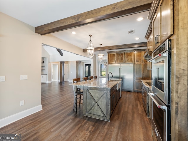 kitchen with a kitchen bar, a center island with sink, light stone countertops, and dark hardwood / wood-style floors