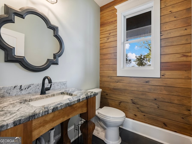 bathroom featuring wood walls, toilet, and sink