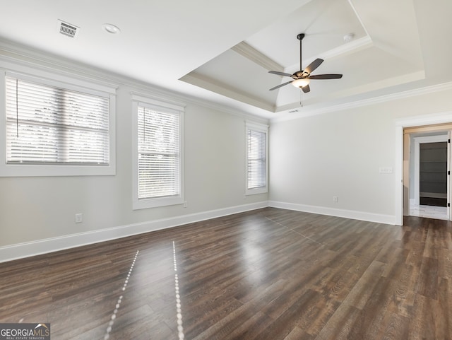 empty room featuring crown molding, a raised ceiling, dark wood-type flooring, and ceiling fan