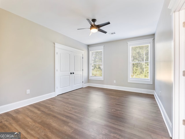 unfurnished bedroom featuring dark wood-type flooring, ceiling fan, and a closet