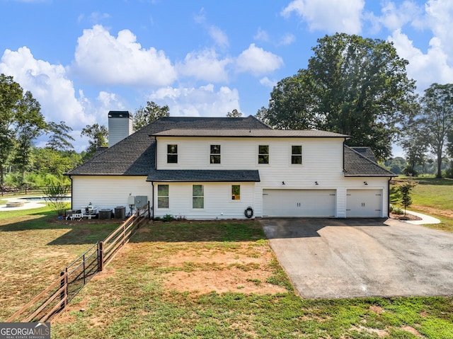 rear view of house with a garage, a lawn, and central AC unit