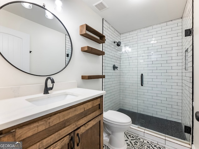 bathroom featuring tile patterned flooring, vanity, toilet, and a shower with shower door