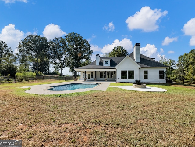 rear view of property featuring a fenced in pool, a lawn, and a patio