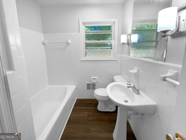 bathroom featuring hardwood / wood-style floors, bathing tub / shower combination, tile walls, toilet, and decorative backsplash