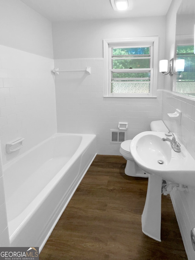 bathroom featuring tile walls, toilet, shower / washtub combination, and hardwood / wood-style flooring