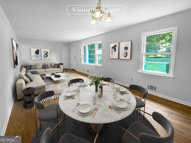 dining room with plenty of natural light, a notable chandelier, and light wood-type flooring