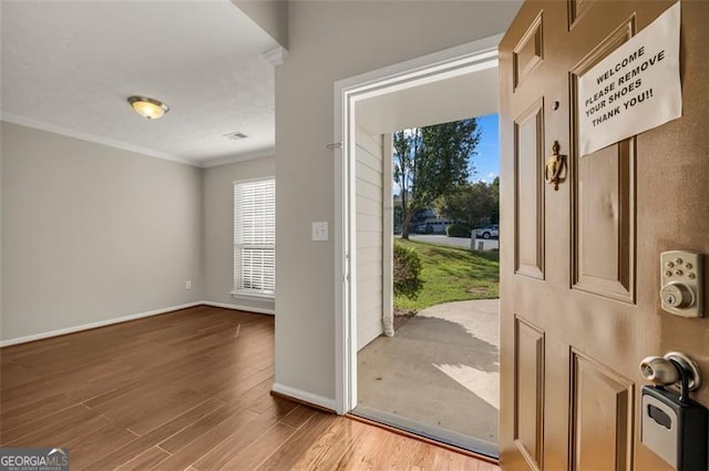 foyer with crown molding and light hardwood / wood-style floors