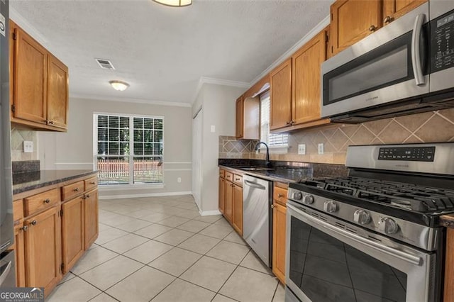 kitchen featuring a wealth of natural light, backsplash, sink, and appliances with stainless steel finishes