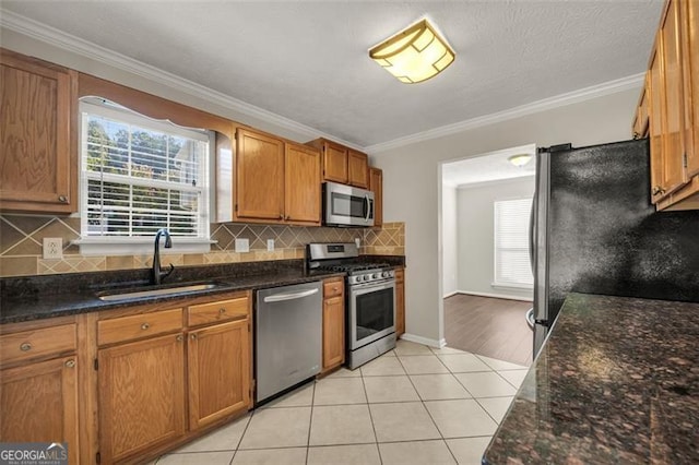 kitchen with ornamental molding, stainless steel appliances, sink, and tasteful backsplash