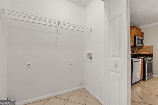 laundry room with crown molding, hookup for a washing machine, light tile patterned flooring, and hookup for an electric dryer