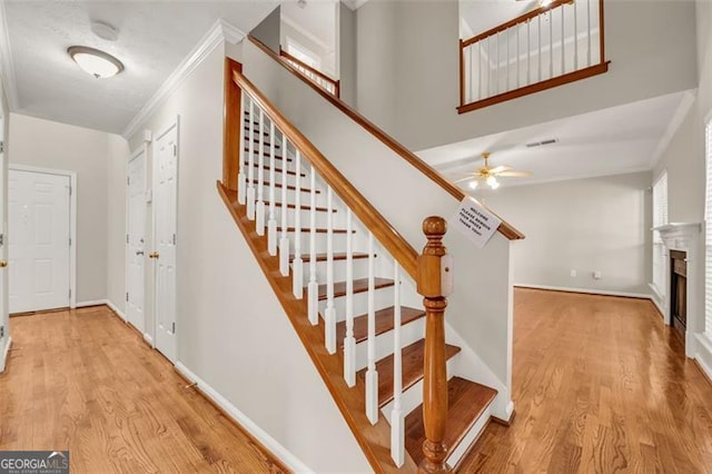 stairway with ceiling fan, ornamental molding, and hardwood / wood-style floors