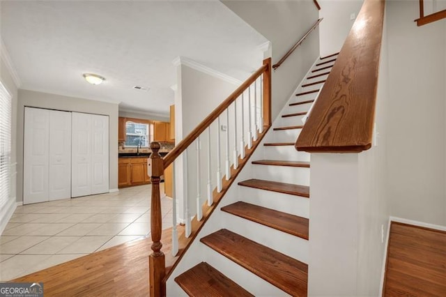 stairway featuring ornamental molding and hardwood / wood-style flooring