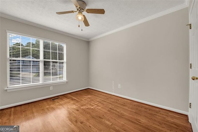 empty room featuring ceiling fan, ornamental molding, wood-type flooring, and a textured ceiling