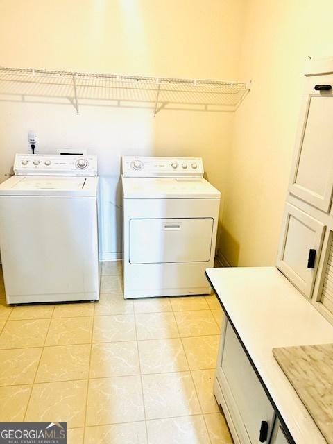 laundry area featuring light tile patterned floors, cabinets, and independent washer and dryer