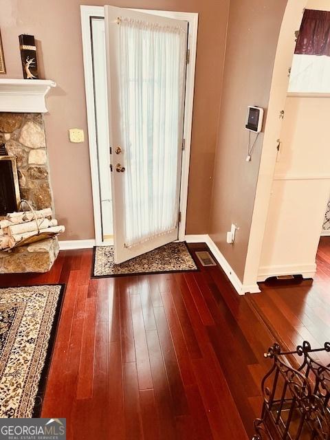 doorway to outside with dark hardwood / wood-style flooring and a stone fireplace