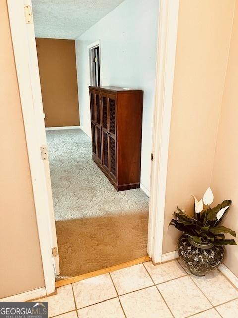 corridor with a textured ceiling and light tile patterned floors