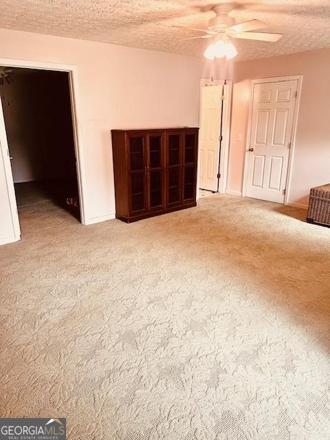 carpeted spare room with ceiling fan and a textured ceiling