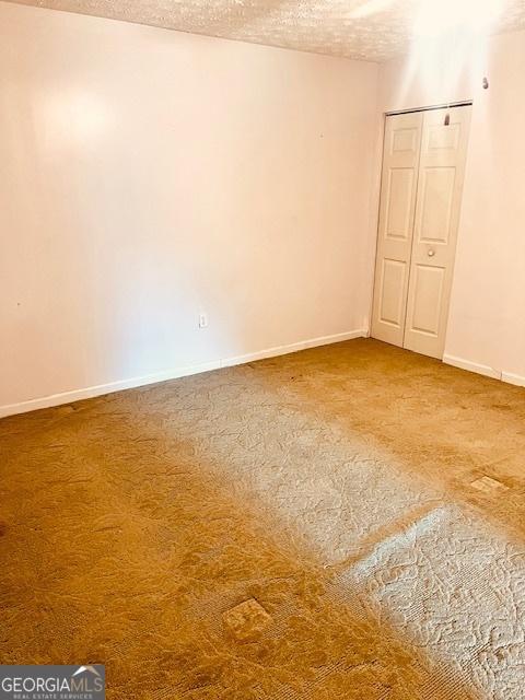 carpeted empty room with a textured ceiling