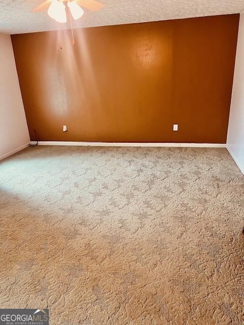 unfurnished room featuring a textured ceiling, carpet floors, and ceiling fan