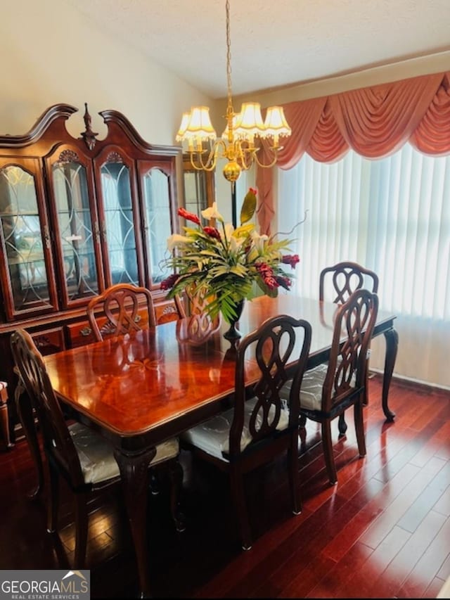 dining room with dark hardwood / wood-style flooring and an inviting chandelier