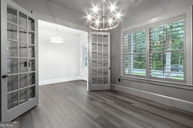 unfurnished dining area featuring french doors, a chandelier, and dark hardwood / wood-style floors