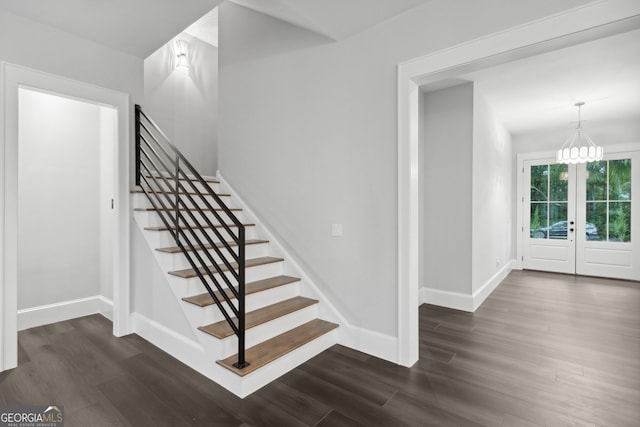 staircase with hardwood / wood-style floors, an inviting chandelier, and french doors