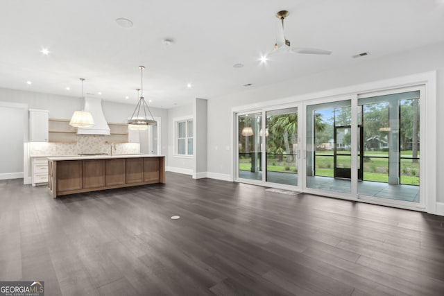 unfurnished living room with ceiling fan and dark wood-type flooring